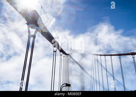 Golden Gate Bridge vu à travers le brouillard qui ondulent et lens flare hexagones. Vue rapprochée des câbles et la tour. Ciel bleu au-delà du brouillard. Copier l'espace. Banque D'Images