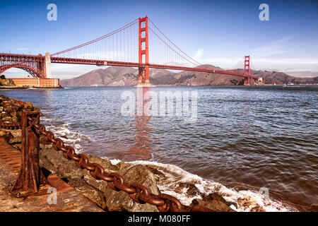 Golden Gate Bridge. Avant-plan d'eau, blocs rocheux et une lourde chaîne rouillée garde-corps. Banque D'Images