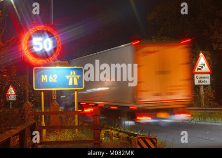 Camion passant réduit avertissement de limite de vitesse 50mph signe sur l'autoroute M62 la nuit Leeds yorkshire royaume uni Banque D'Images