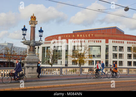 Les cyclistes traversant le pont bleu décoratif Blauwbrug) (1883) avec Nationale Opera and Ballet dans le bâtiment Stopera en arrière-plan, Amsterdam, Pays-Bas Banque D'Images