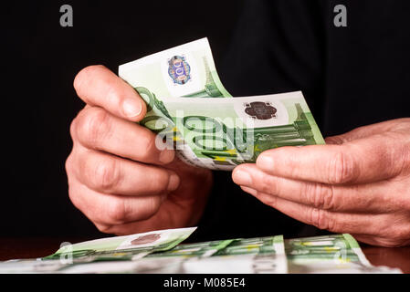 La main de 100 billets en euros, qui sont comptés et mis sur une table. Banque D'Images