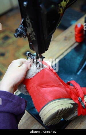 Dans un magasin de chaussures cordonnier coud sur la machine à coudre sur les bottes de verrouillage Banque D'Images