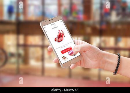 9 fois en ligne avec l'app du commerce ou site web. Woman holding smart phone moderne. Centre commercial d'arrière-plan. Banque D'Images