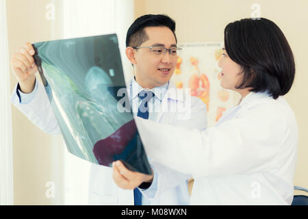 Deux médecin parler et examining x-ray film sur fond flou et résultat salle d'opération avec X-ray scanner médical à l'hôpital. Banque D'Images