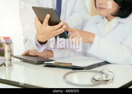 Deux médecins l'analyse et de consultation sur dossier médical de l'hôpital moderne. Les médecins asiatiques parle de rapport. Banque D'Images