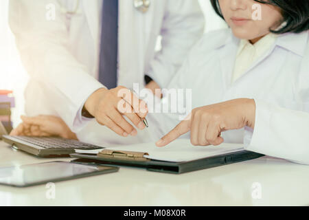 Deux médecins l'analyse et de consultation sur dossier médical de l'hôpital moderne. Les médecins asiatiques parle de rapport. Banque D'Images