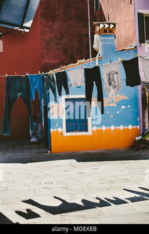 Blanchisserie hanging in a sunny vide arrière-cour de l'île de Burano, Venise. Banque D'Images