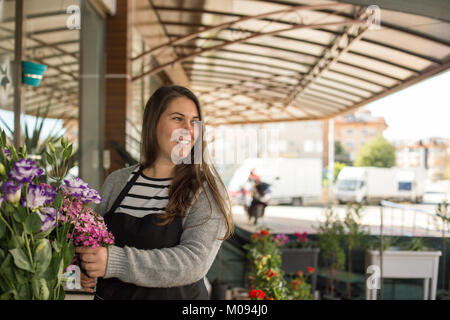 Small business concept. Femme Smilng la cueillette des fleurs fleuriste dans un magasin de fleur. Banque D'Images