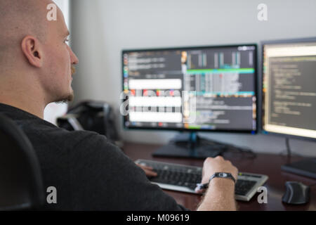 Le code de programmation de l'homme sur les ordinateurs à l'écran 24. Banque D'Images