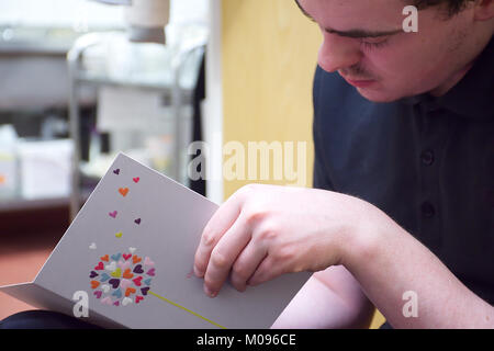 Un homme écrit des jeunes adultes carte de la Saint-Valentin pour sa petite amie pendant la pause dans le travail.Lichfield Staffordshire, Royaume-Uni,13,janvier,2018. Banque D'Images