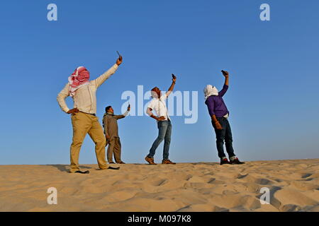 Groupe d'hommes faisant autoportraits dans le désert et portant leurs foulards de tête traditionnel Banque D'Images