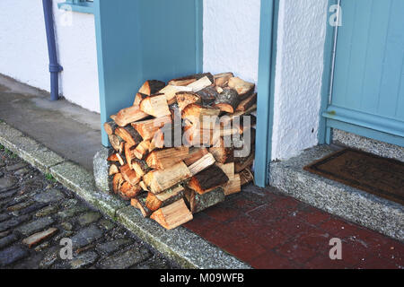 Pile de bois de chauffage à l'extérieur de la porte d'une chambre intérieure - John Gollop Banque D'Images