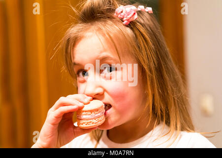 Petite fille de mordre un gâteau rose Banque D'Images