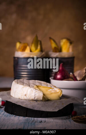 Photo verticale avec un camembert rôti à la peau blanche. Le fromage est partiellement fondu. Boîtes vintage avec pommes de terre rôties et les oignons soient de couleur Banque D'Images