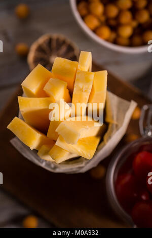 Verticall photo avec vue de dessus sur vintage vieux peut occupés par du papier et fine orange / jaune bois fabriqué à partir de fromage gouda. Pouvez est le conseil en bois vintage Banque D'Images