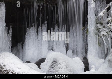 Froide journée d'hiver. L'écoulement de l'eau brouillée avec cascade, rochers dans un ruisseau ou un cours d'eau. Banque D'Images