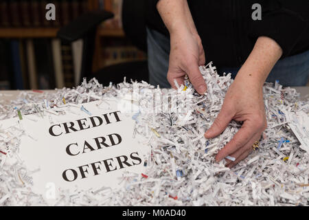 Une femme a les mains illustré par le tri du papier déchiqueté par les mots CARTE DE CRÉDIT offre à côté d'elle. Banque D'Images