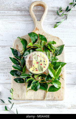 Le pâté de foie de poulet pot couvert de beurre fondu et décoré avec les feuilles de laurier et du poivre noir et rouge. Fond rustique en bois blanc. Vue de dessus, Fl Banque D'Images