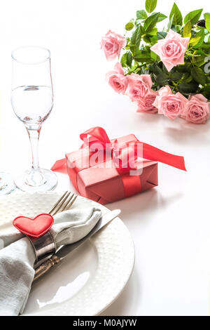 Valentines Day le dîner avec table place setting with red gift, verre de champagne, ornements coeur avec l'argenterie. Close up. Carte de la Saint-Valentin. Banque D'Images