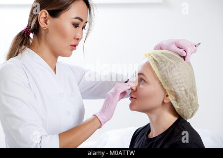 Intervention cosmétique pour la correction des pommettes à l'aide d'injections de Botox. Femme médecin asiatique de perforations dans la pommette de botox d'une jeune femme Africa Banque D'Images