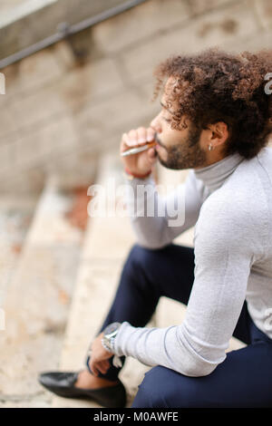 Jeune fumeur mulâtre de la toux sur les mesures avec la cigarette. Banque D'Images