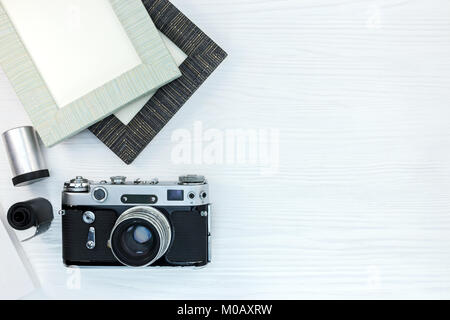 Ancien appareil photo rétro, les rouleaux de film négatif et cadres de photo vides sur fond de bois blanc vue plate Banque D'Images