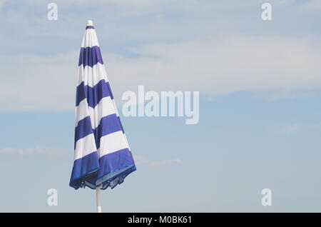 Fermé rayé bleu et blanc Parasol contre Ciel Bleu d'été Banque D'Images