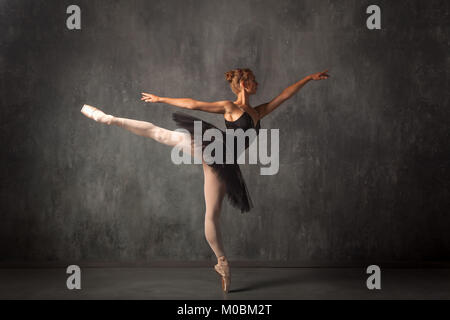 Belle femme blonde attrayant primer dans une ballerine danse noir pack, blanc collant et les pointes des danses magnifiquement dans un sombre ballet studio Banque D'Images