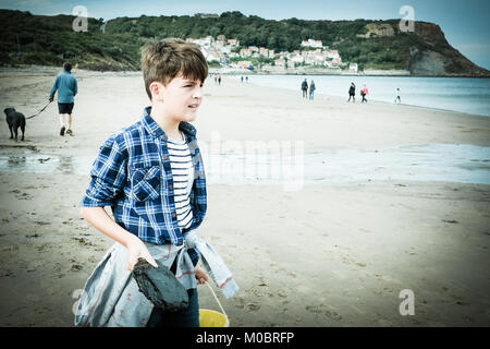 10 ans garçon brun foncé profiter le temps des vacances sur la plage, Runswick Bay, Yorkshire, UK. Banque D'Images