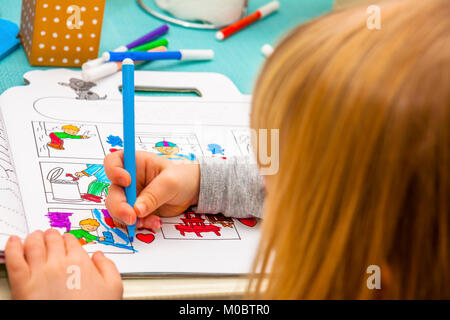 Gros plan du dessin avec des crayons de couleur de fille dans un livre à colorier Banque D'Images