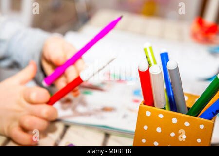 Gros plan du dessin avec des crayons de couleur de fille dans un livre à colorier Banque D'Images