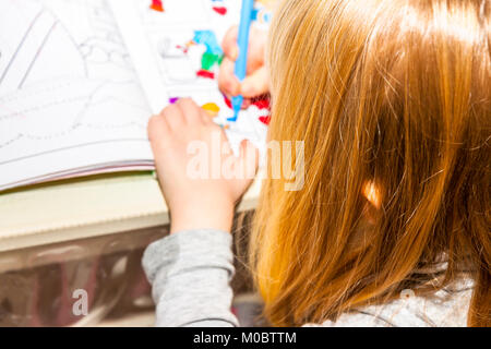 Gros plan du dessin avec des crayons de couleur de fille dans un livre à colorier Banque D'Images