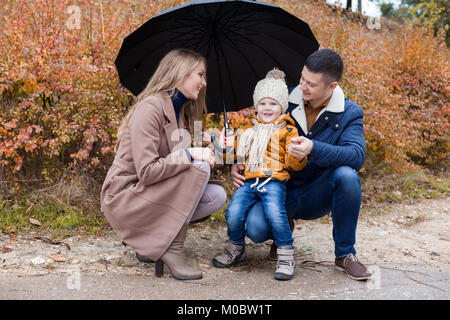 L'automne de la famille dans le parc sous la pluie parapluie Banque D'Images