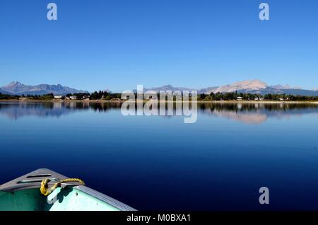 Une belle réflexion sur la montagne calme d'un lac glaciaire au Montana, avec le nez d'un bateau de pêche montrant en bas à gauche. Banque D'Images