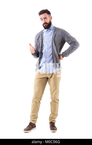 Barbu élégant smart casual guy wearing cardigan showing thumb up geste et regarde la caméra. La pleine longueur du corps portrait isolé sur fond blanc Banque D'Images