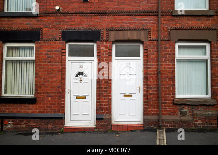 Les portes en PVC blanc moderne sur deux chambres mitoyennes de style victorien en briques rouges ward street St Helens merseyside uk Banque D'Images