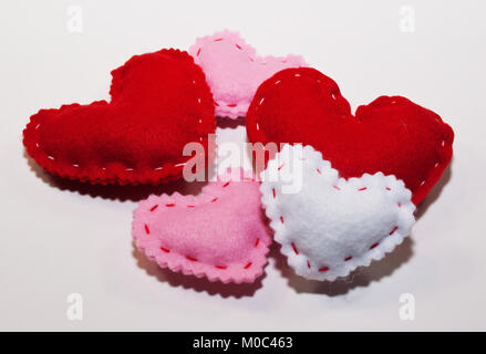 Tissu artisanal cinq cœurs, deux rouges, deux petites roses et un petit blanc sur fond blanc Banque D'Images