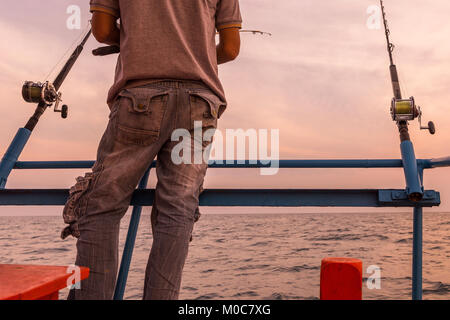 Pêcheur asiatique et canne à pêche sur le bateau de pêcheur sur la mer Banque D'Images