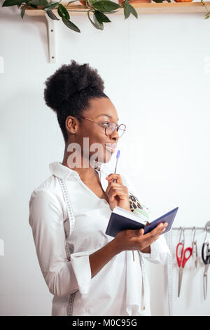 Jeune fille africaine couturière prendre des notes à l'ordinateur portable. designer croquis dessin Banque D'Images