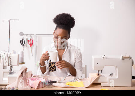 Cheerful woman couturière tablier en parlant au téléphone et de boire du café Banque D'Images