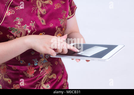 Young Asian woman wearing dress cheongsam chinois traditionnel ou qipao. Mains tenant et de carte de crédit à l'aide d'ordinateur portable. Les achats en ligne. Concept de l'achat Banque D'Images