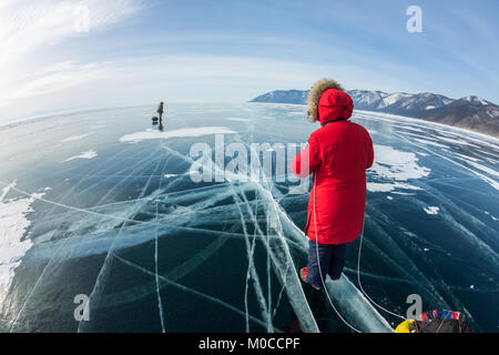 Femme avec un traîneau à pied est sur la glace du lac Baïkal. Banque D'Images