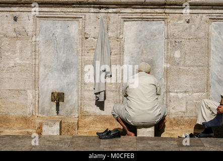 Bain turc musulman se lave les pieds en face d'une mosquée Banque D'Images