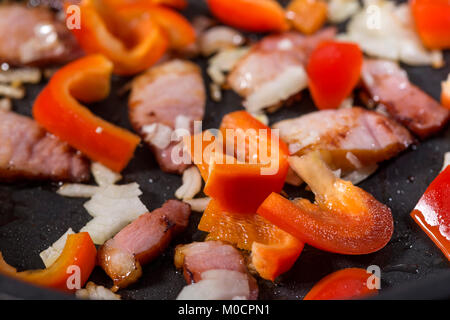 Les légumes hachés, l'oignon, poivron et jambon de porc lors de la cuisson dans une poêle Banque D'Images