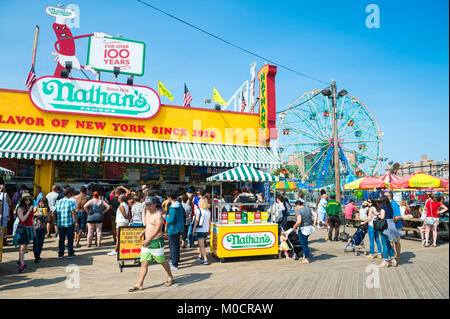 NEW YORK - 20 août 2017 : visiteurs se pressent l'emblématique promenade de Coney Island en bois à l'extérieur de la célèbre Nathan's hot dog sur une chaude journée d'été Banque D'Images