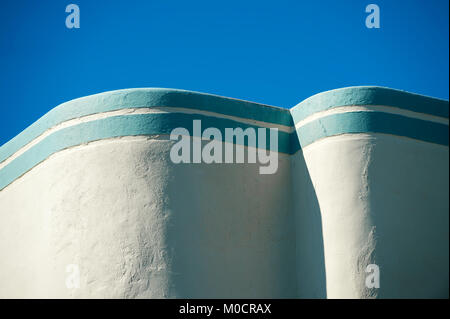 Architectural Abstract close-up d'un mur Art Déco en courbe surmonté d'une bande bleue Méditerranée détail sous le ciel clair Banque D'Images