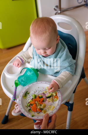 Jeune bébé 1 ans, fille, enfant de manger sain pour le dîner de légumes et des bâtonnets de poisson Banque D'Images