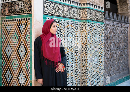 Femme arabe en costume traditionnel avec hijab rouge devant le mur avec du texte de Coran Banque D'Images