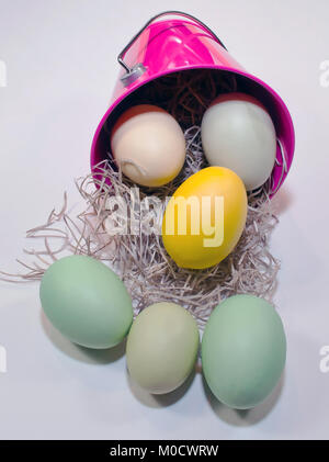 Oeufs de Pâques illustré spilling out of a pink bucket le long avec de la paille sur un fond blanc Banque D'Images