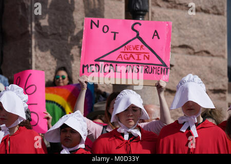 Femme debout derrière les manifestants déguisés en personnages de 'UN Handmaid's Tale' est titulaire d'un signe en faveur de l'avortement au cours d'un rassemblement à la Texas Capitol marquant l'anniversaire de la Marche des femmes 2017 sur Washington et controversée du président Donald Trump, première année en général. Banque D'Images